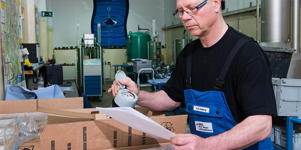 Mitarbeiter hält Wasserzähler und Dokument.